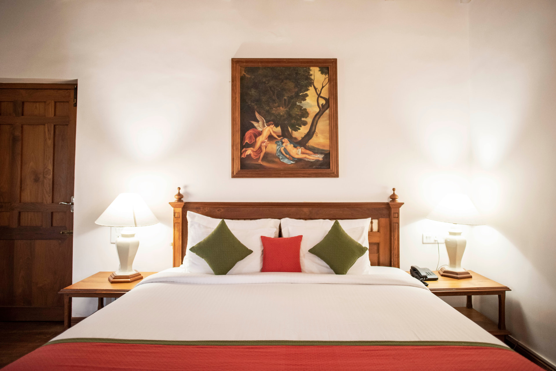 King bed with carved timber headboard and period artwork