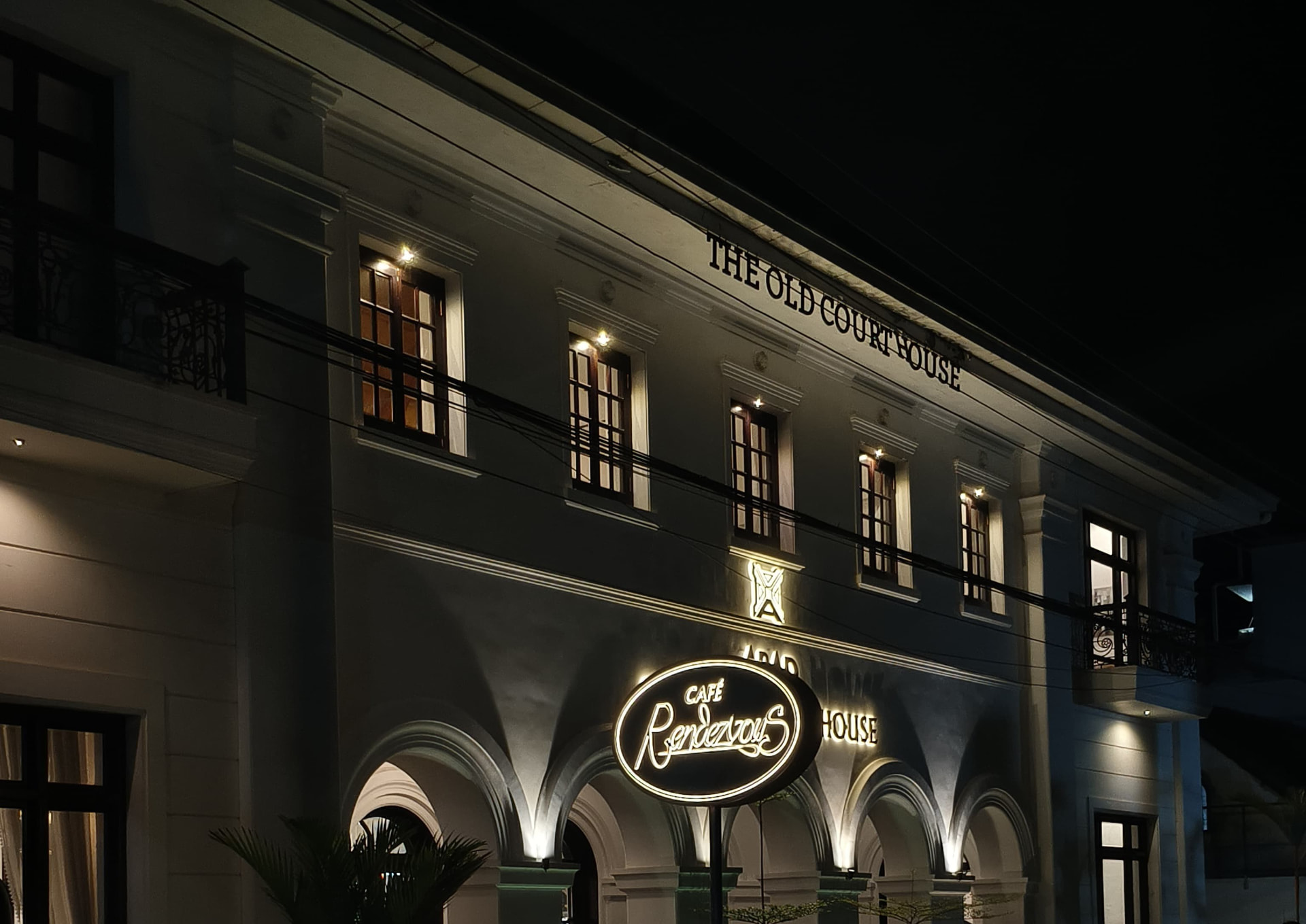 The Old Court House facade illuminated at night with Café Rendezvous signage