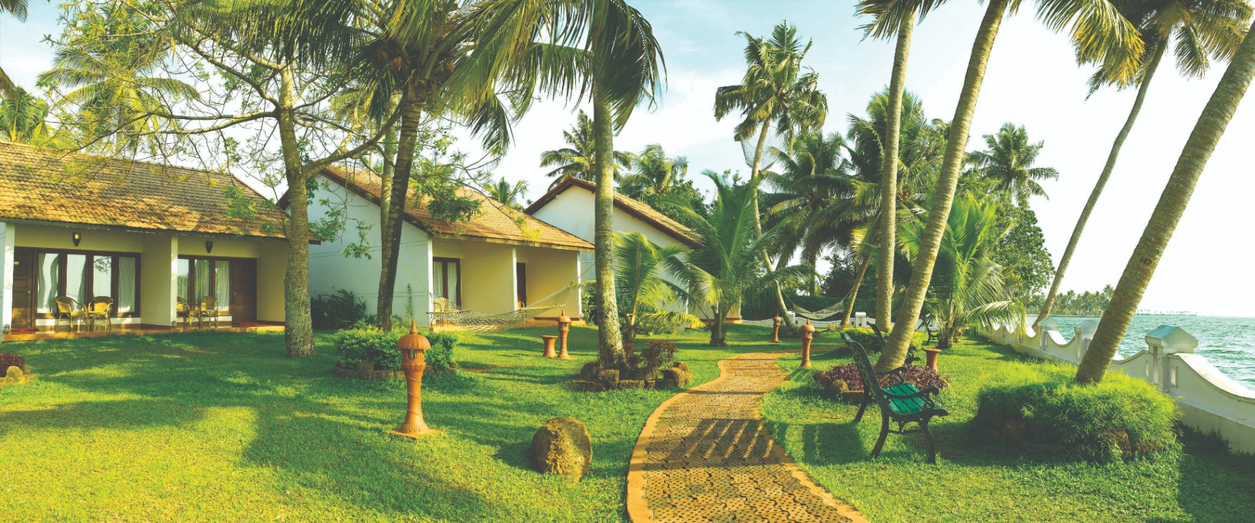 White lake-facing cottages with hammocks on open lawns