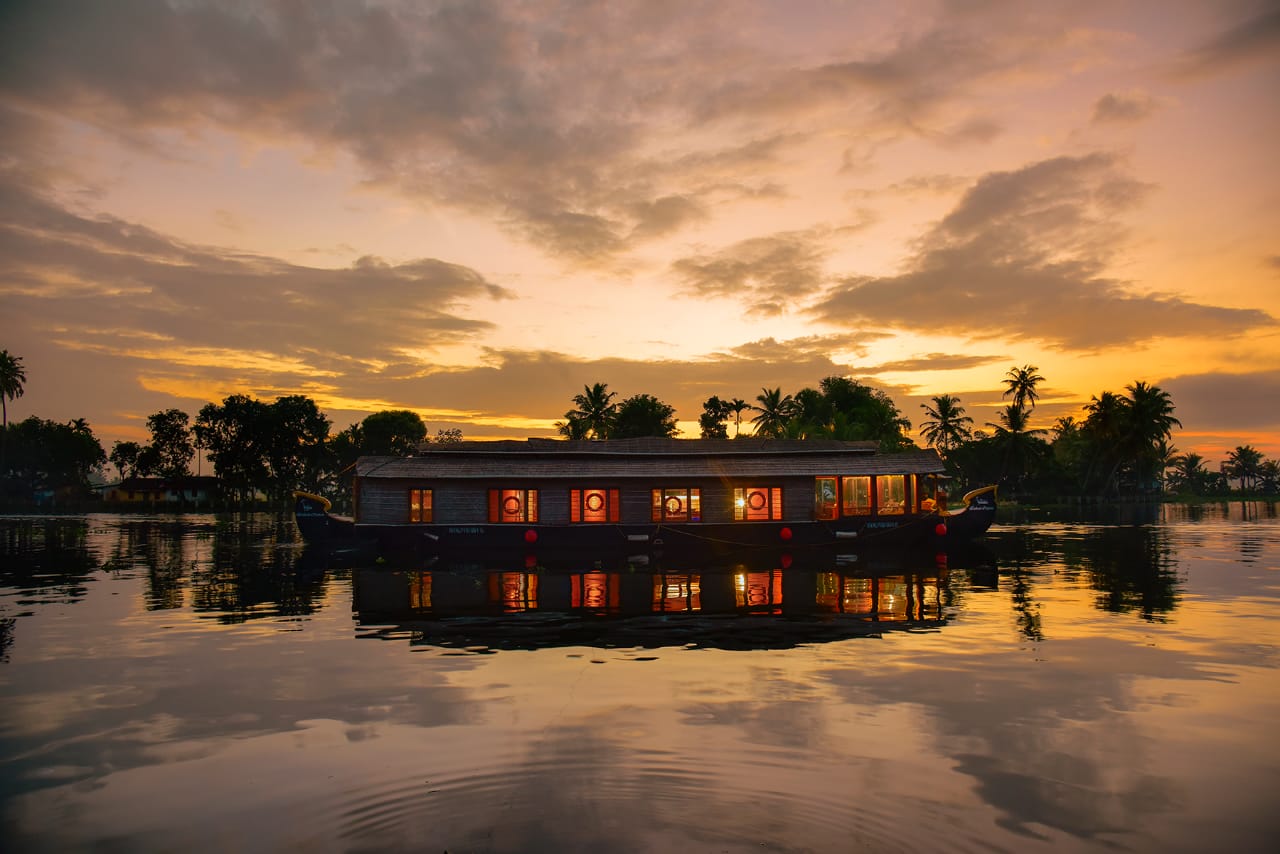 Two bedroom houseboat moored on still backwaters at sunset with lamps lit