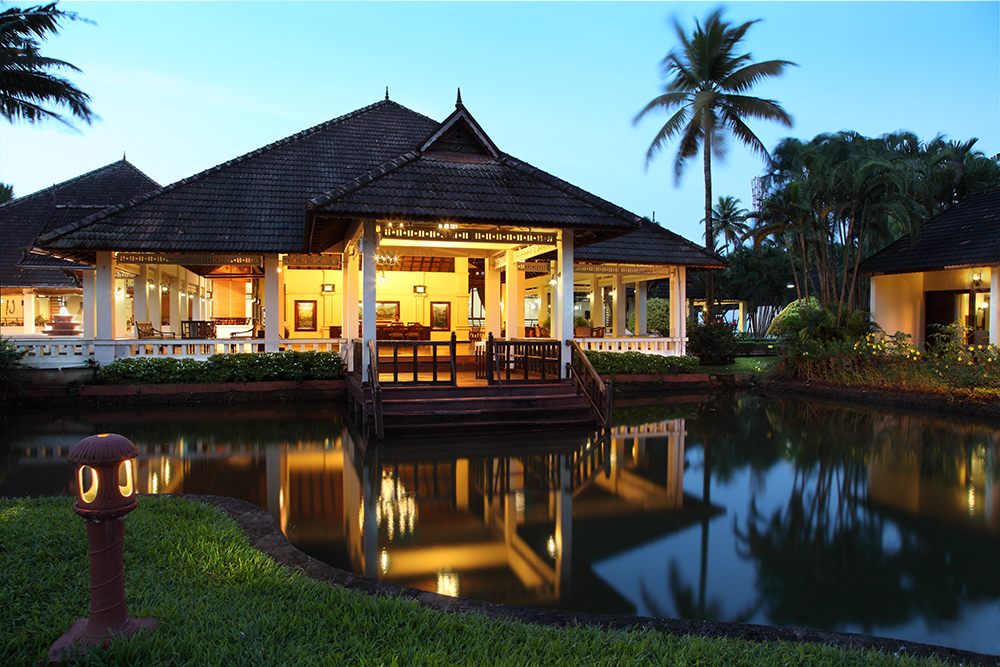 Traditional Kerala-style pavilion reflected in the lotus pond at dusk