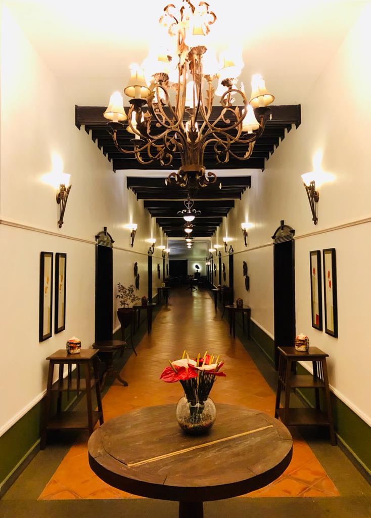 Wrought-iron chandelier above the bungalow corridor with anthurium arrangement