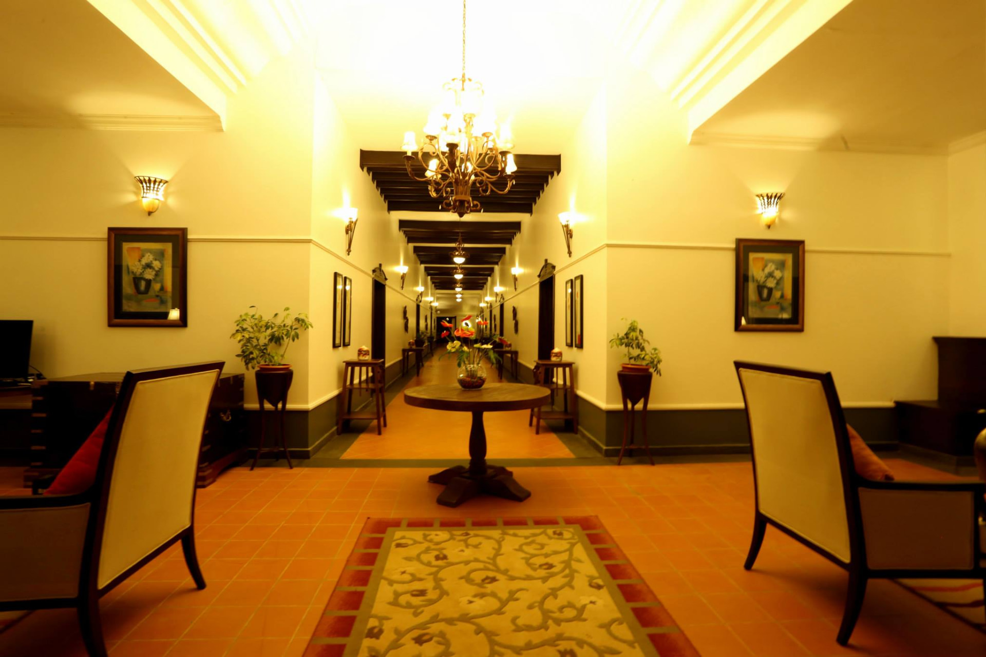 Lobby lounge with armchairs, framed art and a long lit corridor beyond