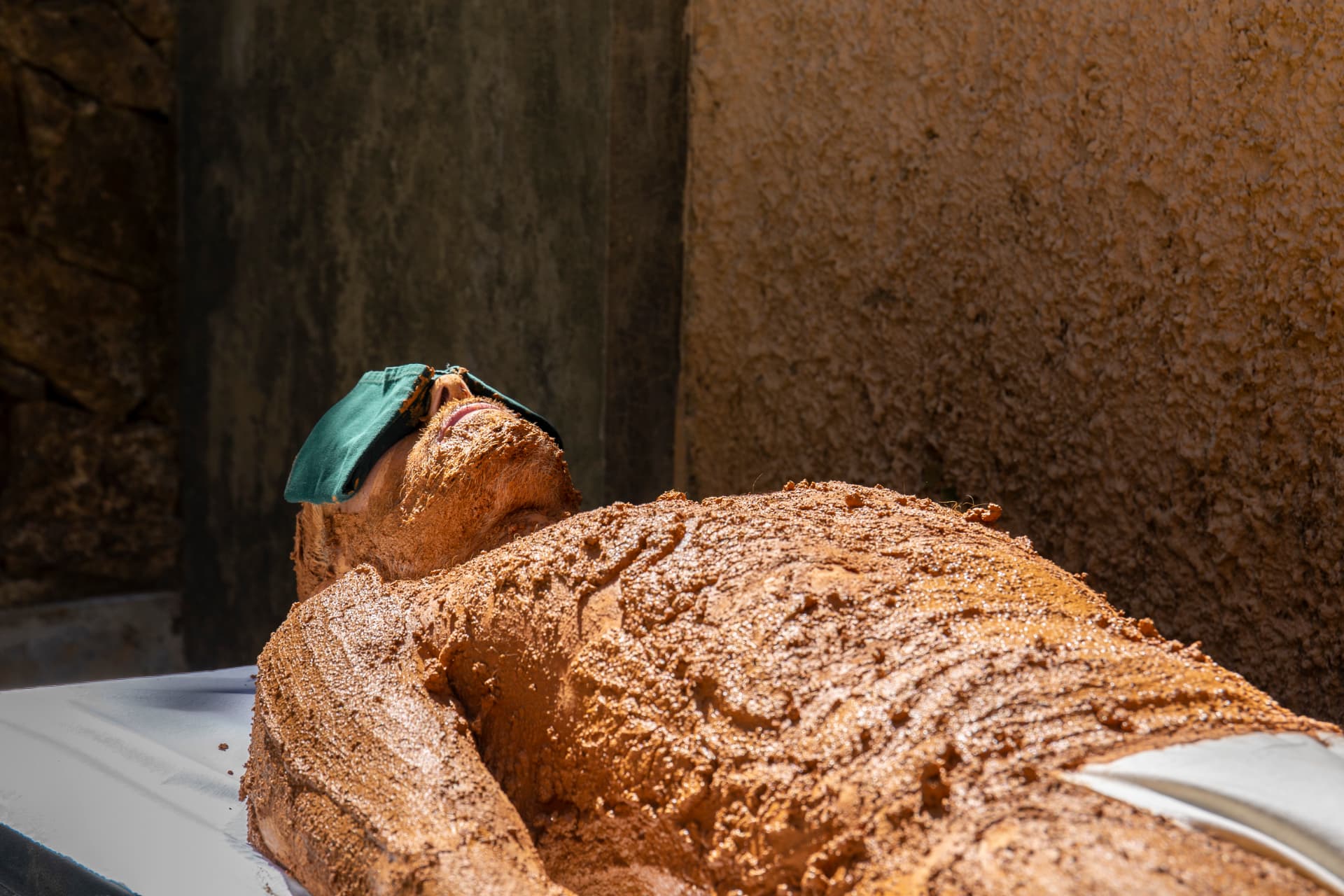 Guest receiving a full-body mud therapy in the open-air treatment court at Prakriti Shakti