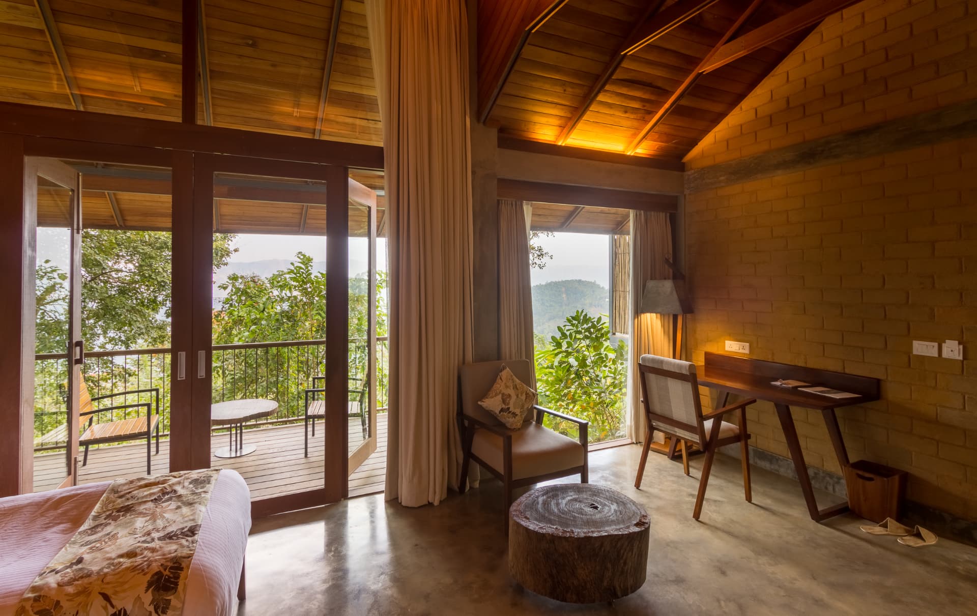 Brick-walled room at Prakriti Shakti opening to a balcony with views across the Western Ghats at sunrise