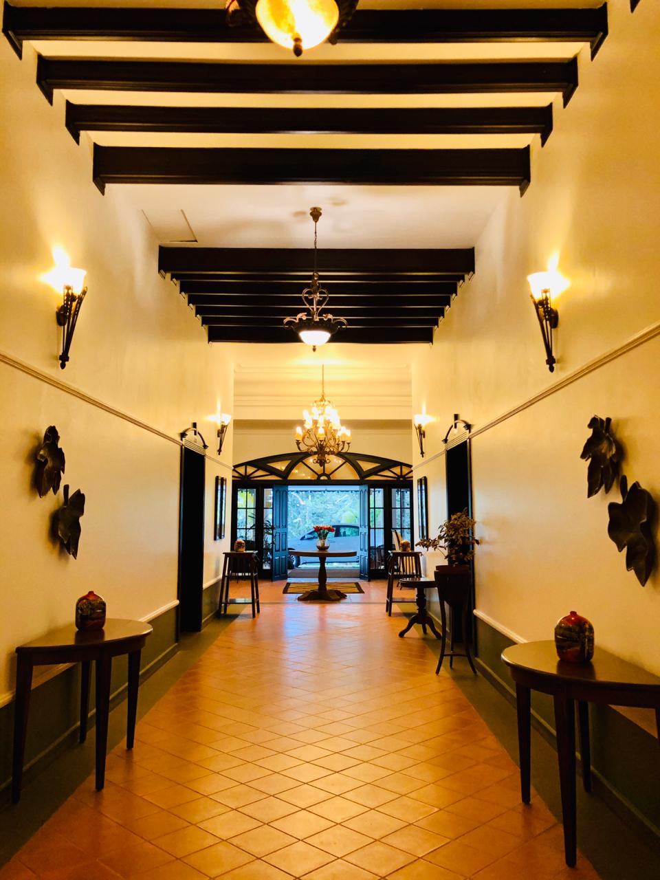 Colonial corridor with timber beams, wall sconces and antique consoles