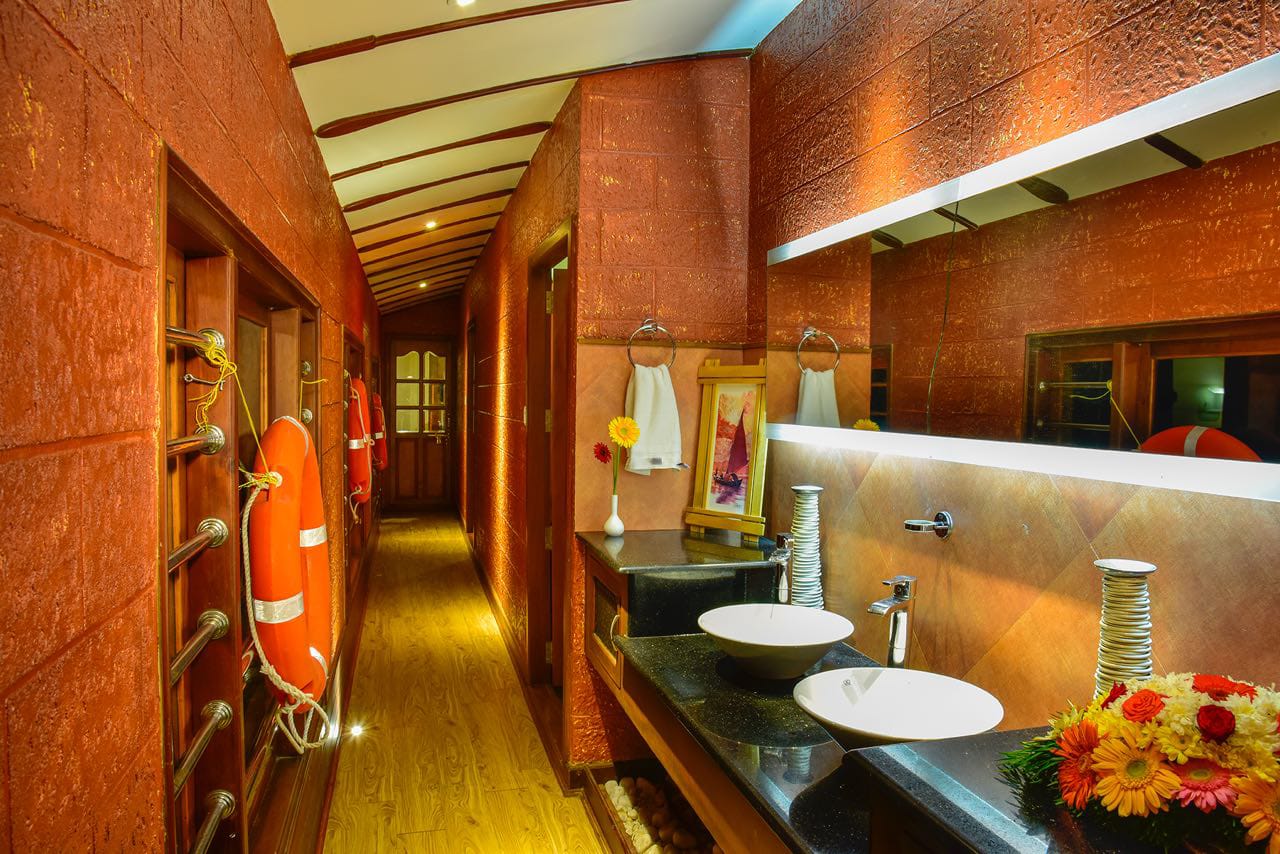 Warmly lit houseboat corridor with twin wash basins and timber flooring