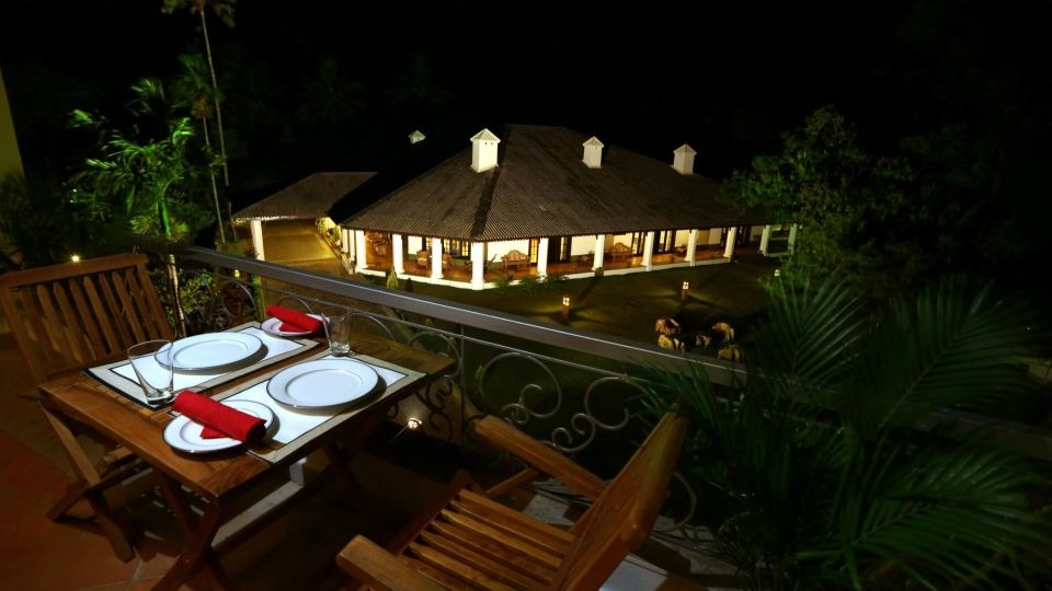 Heritage bungalow lit at night with candlelit terrace dining