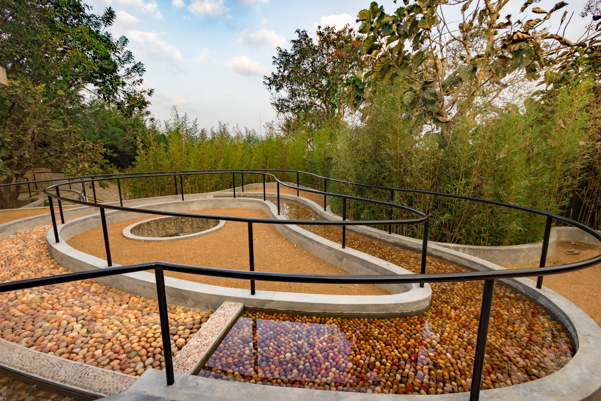 Winding reflexology walk of pebbles, sand and shallow water surrounded by bamboo at Prakriti Shakti