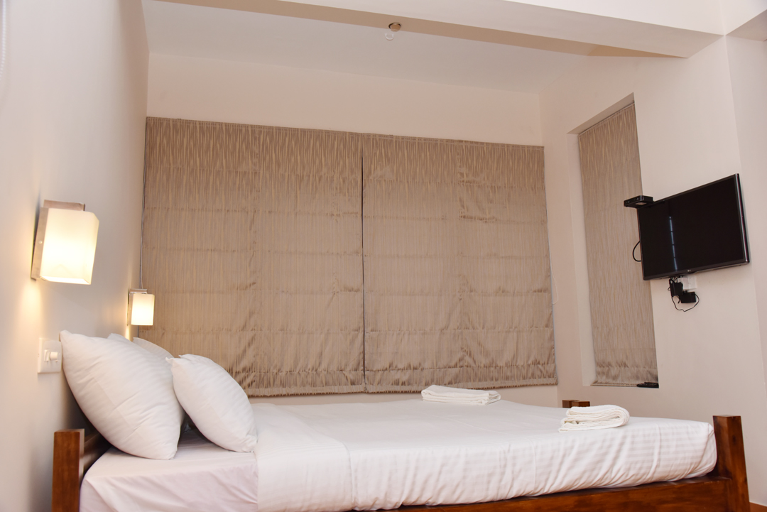 Air-conditioned guest room at Abad Serviced Villas with twin bedside lamps and LED television