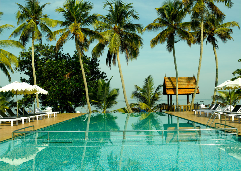 Swimming pool with white umbrellas and coconut palms