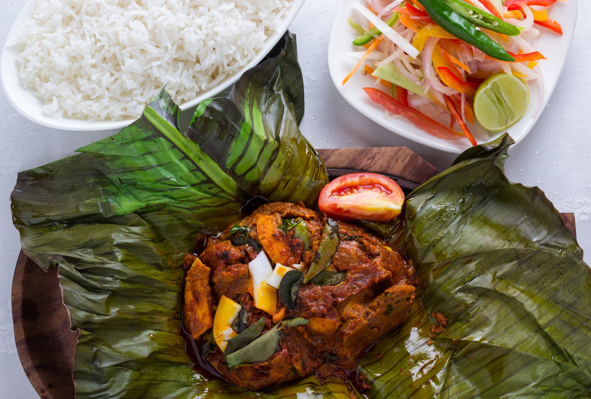 Karimeen pollichathu on banana leaf with rice and salad
