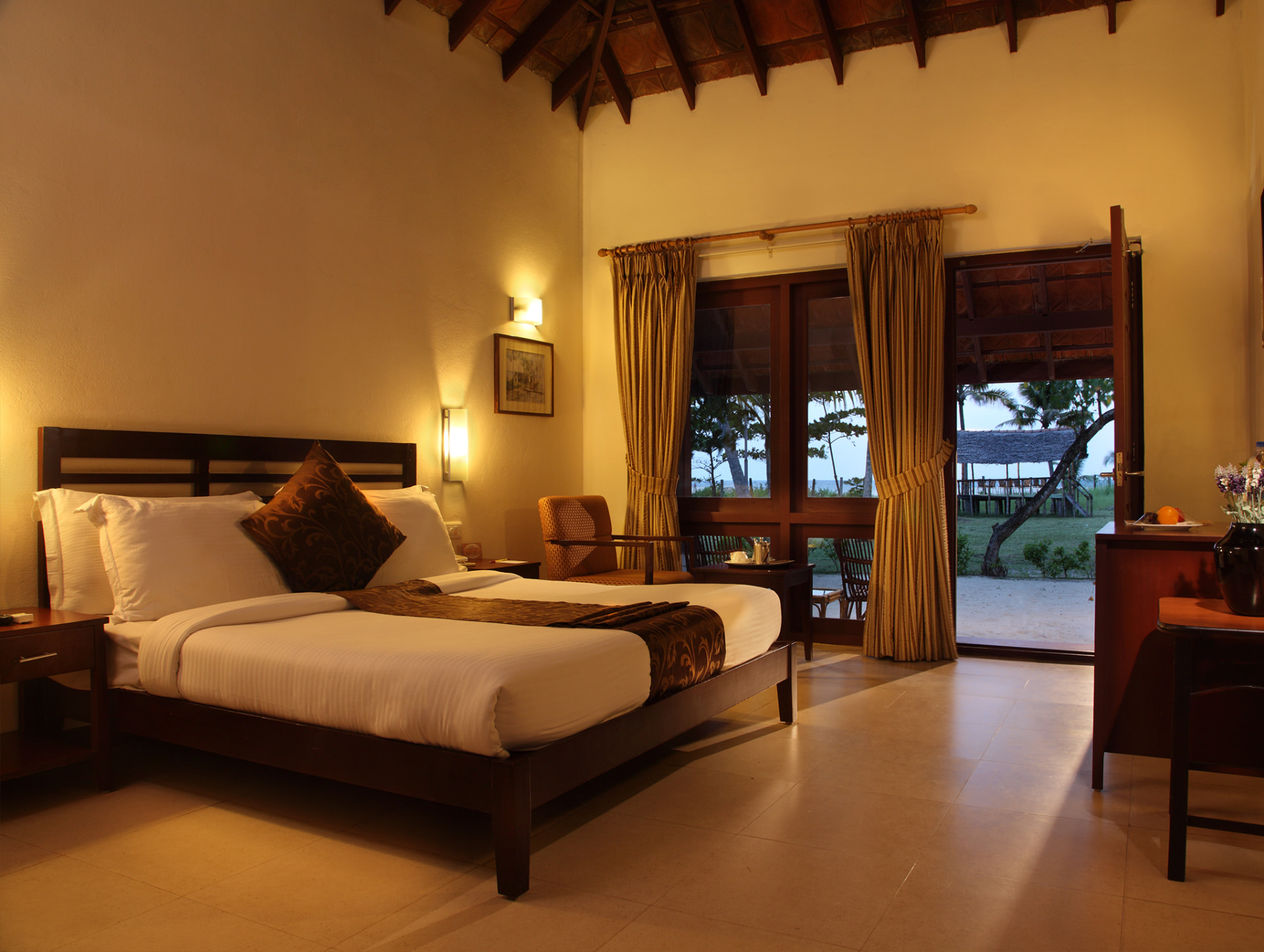 Cottage bedroom with vaulted timber ceiling opening onto the lawn