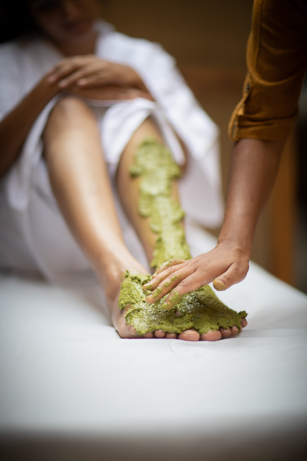 Fresh green herbal paste applied to the leg and foot during a naturopathy therapy at Prakriti Shakti