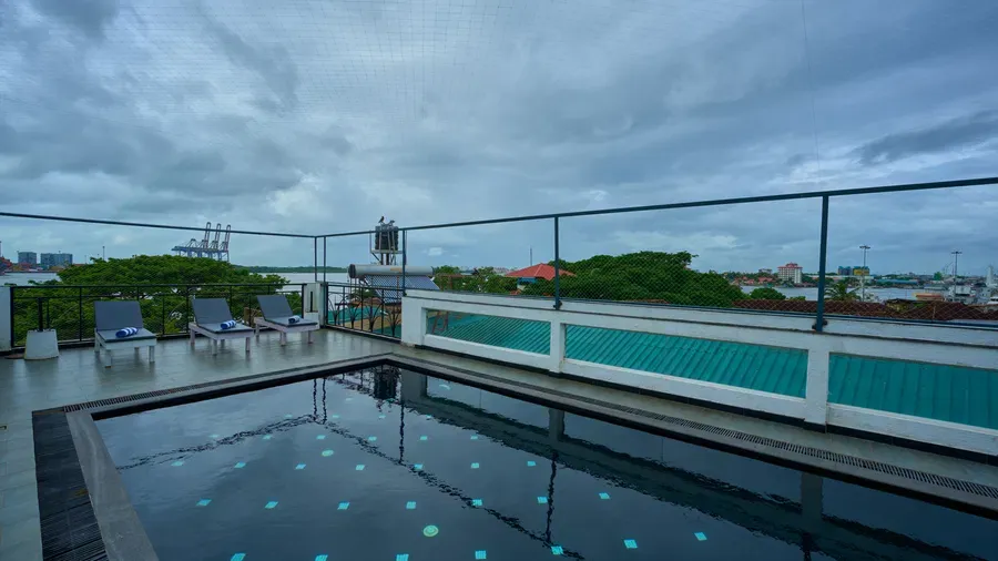 Rooftop swimming pool with loungers overlooking Fort Kochi