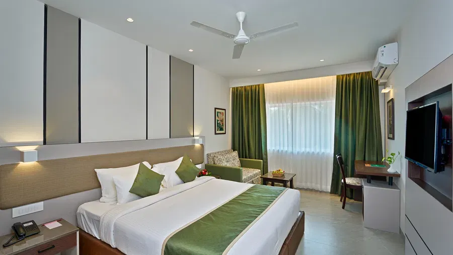 King-bedded room at Abad Fort with armchair and green drapes