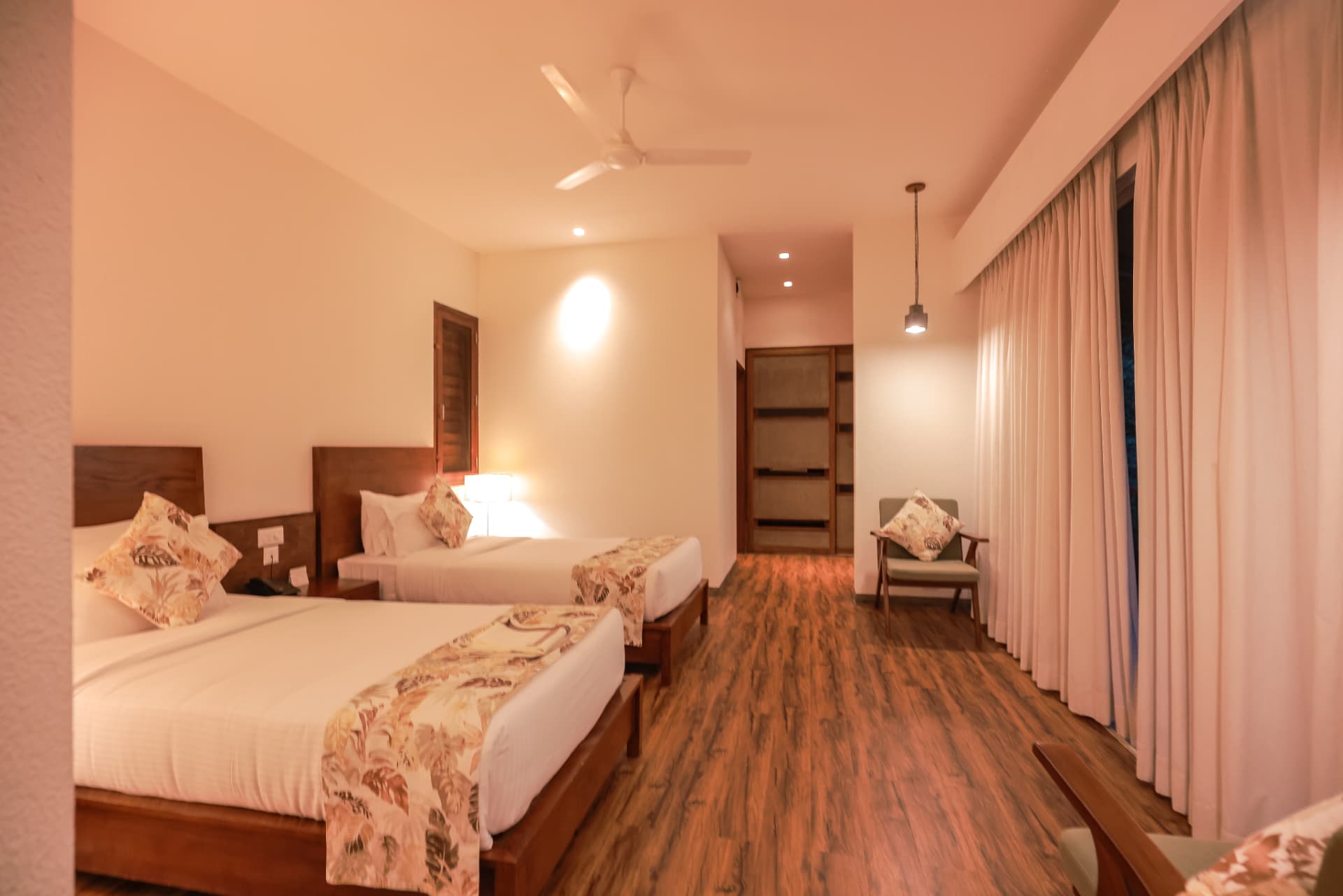 Twin bedded room with warm lamplight and timber floors at Prakriti Shakti, Panchalimedu