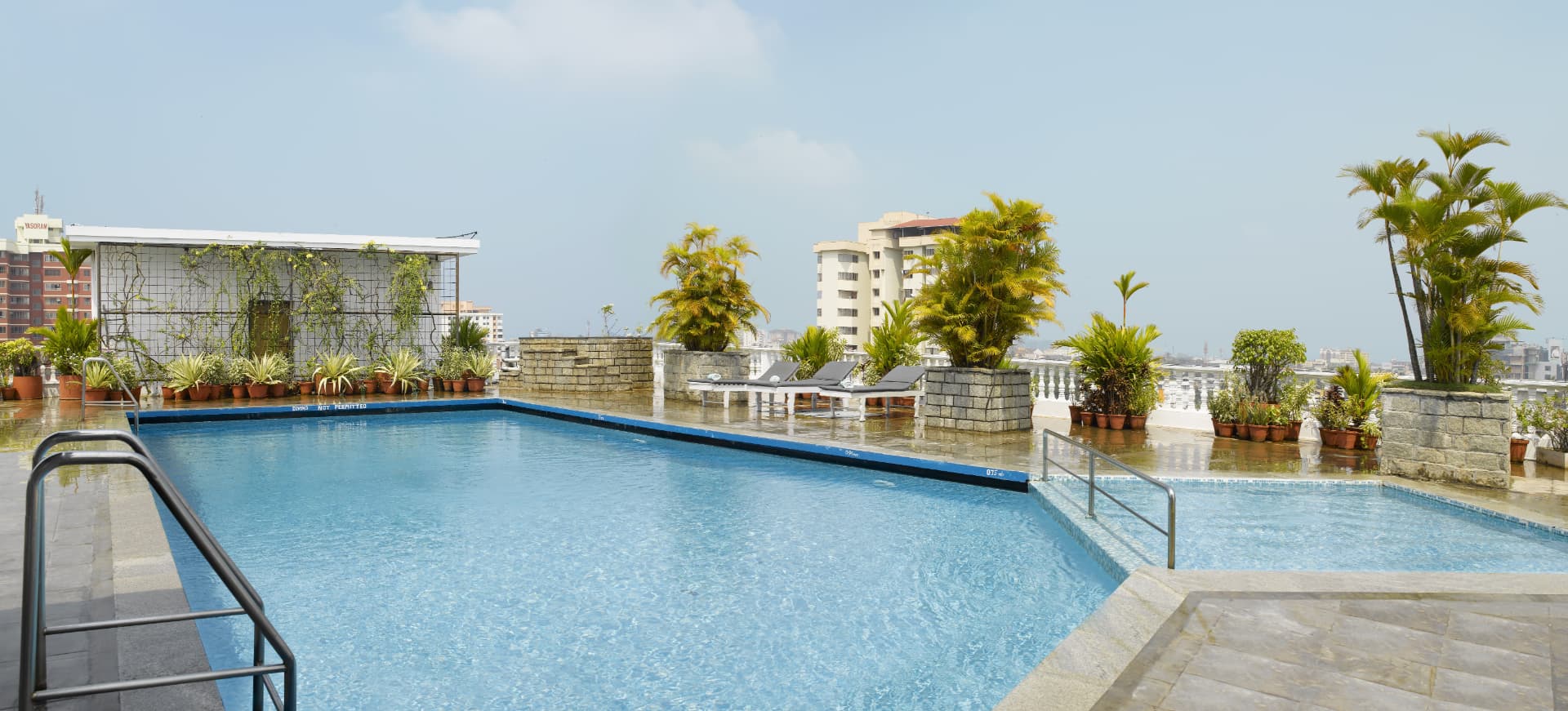 Rooftop swimming pool at Abad Plaza with city views and potted palms