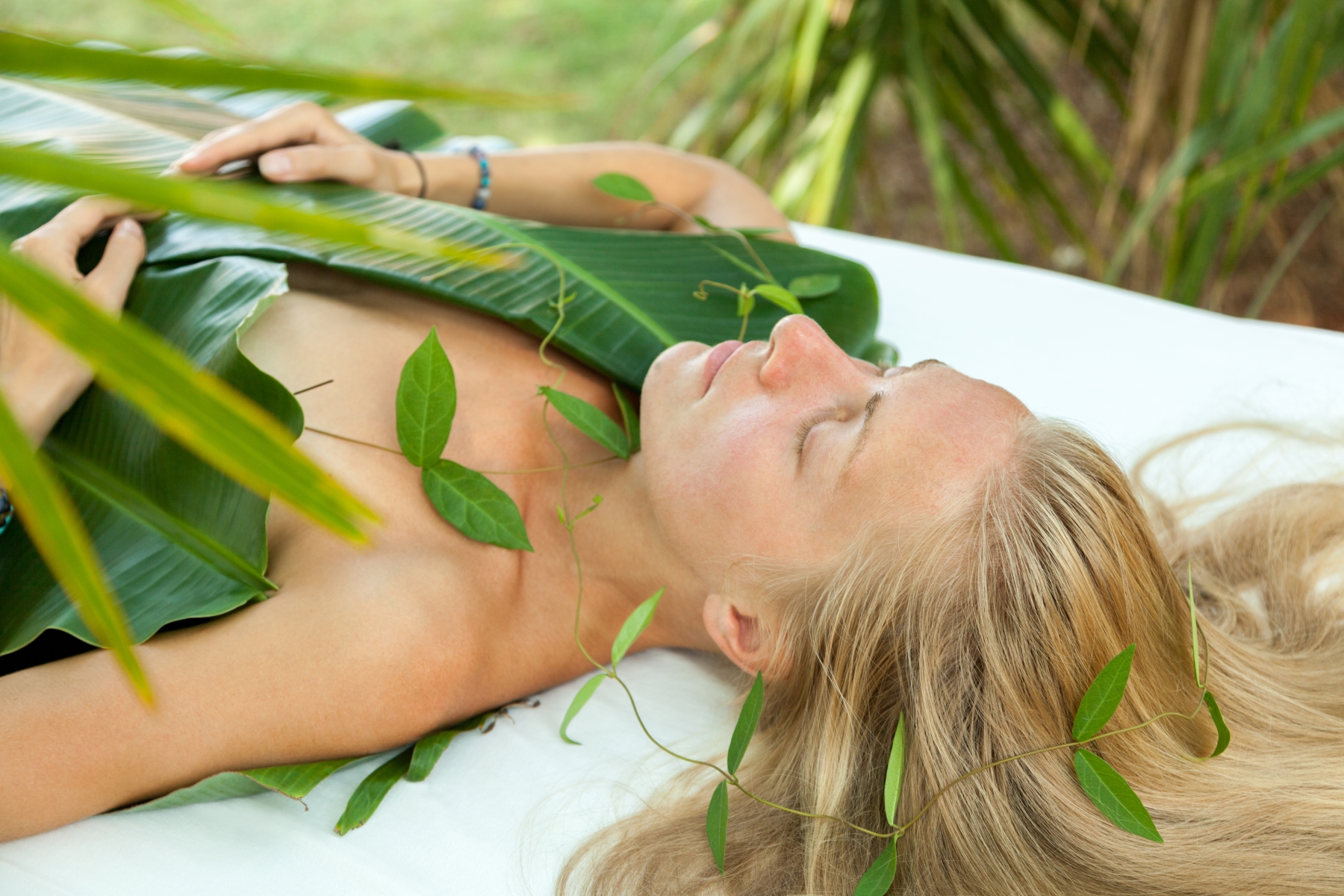 Guest resting beneath fresh banana leaves and vines during a leaf therapy in the garden at Prakriti Shakti