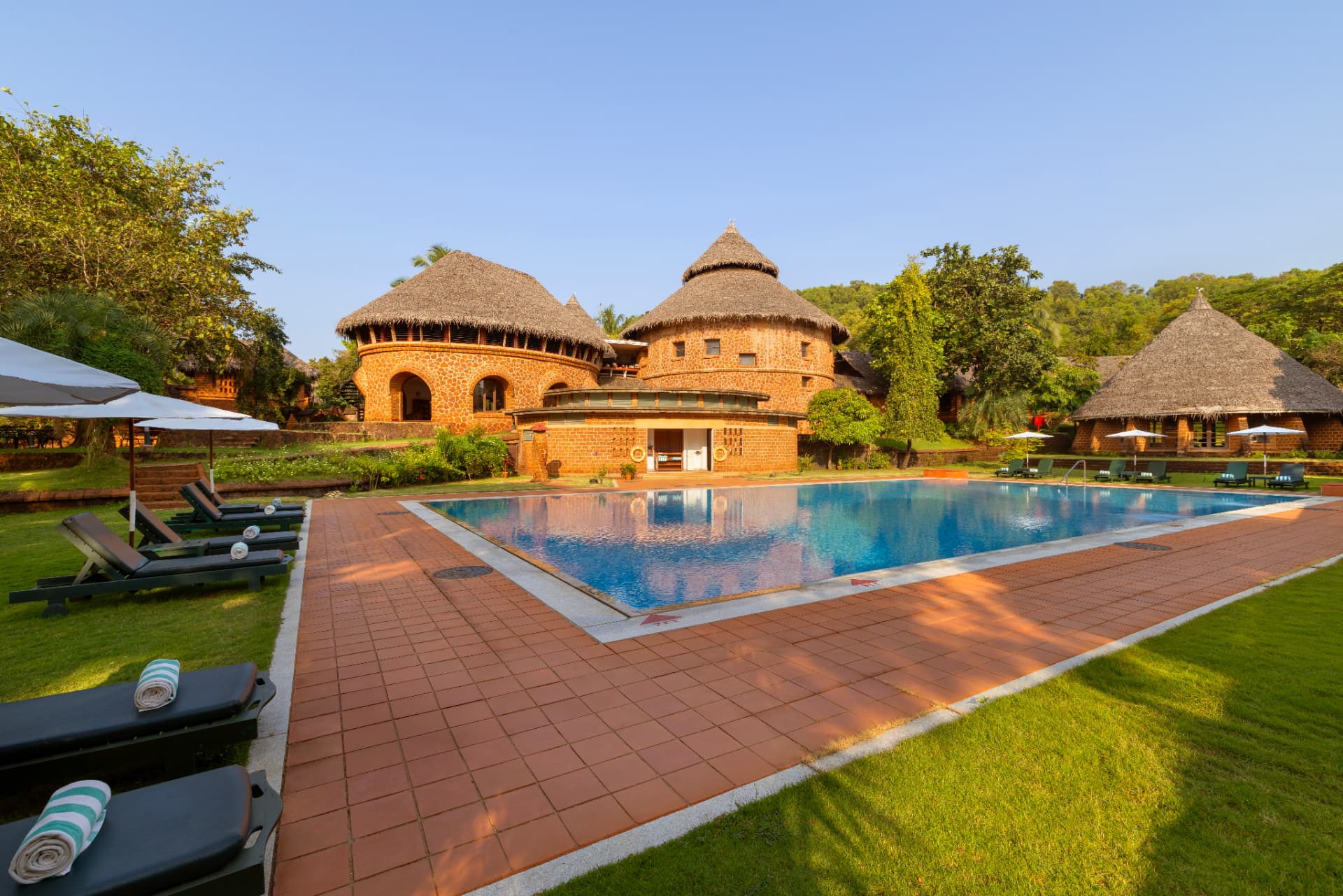 SwaSwara, CGH Earth — laterite pavilions beside the pool