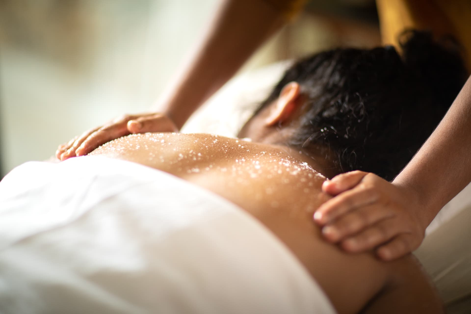 Salt scrub therapy across the back in soft daylight at Prakriti Shakti, Kerala