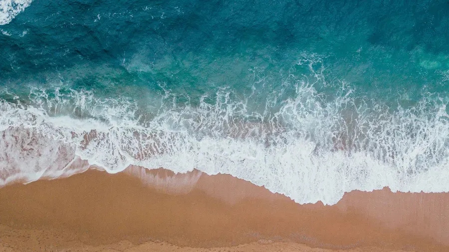 Aerial view of waves meeting the sands of Kovalam Beach