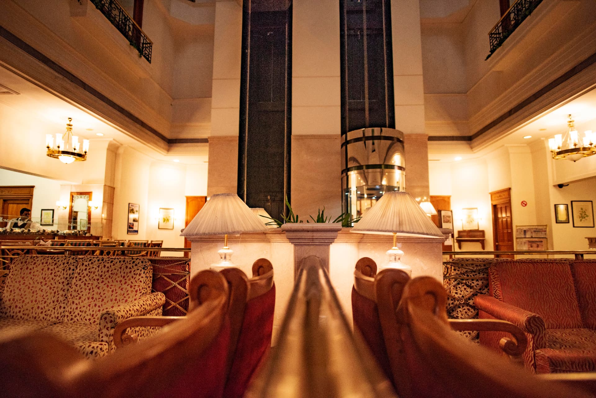 Lobby lounge armchairs and table lamps beneath the glass capsule lifts