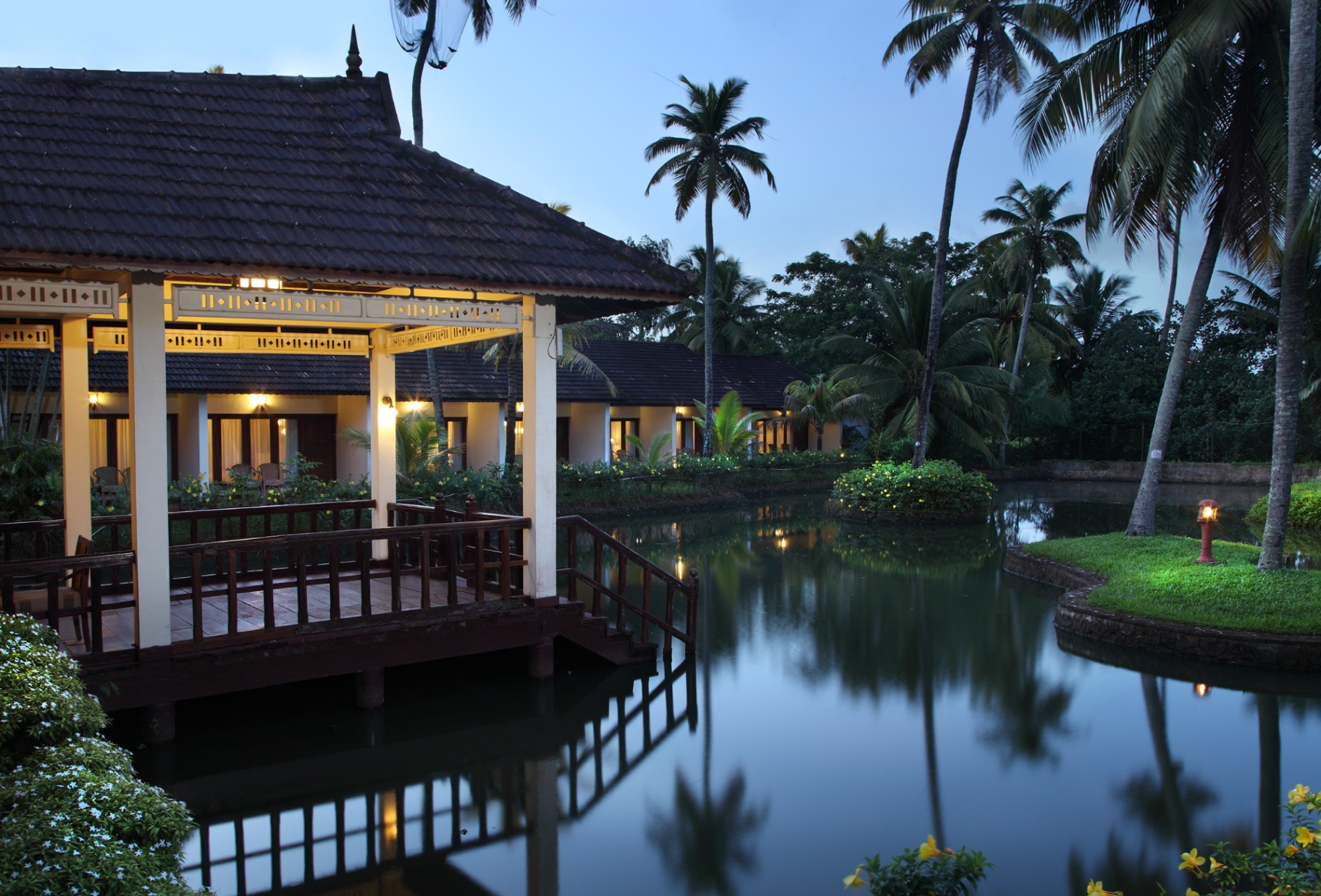 Illuminated pavilion and garden cottages beside the resort's private pond at twilight