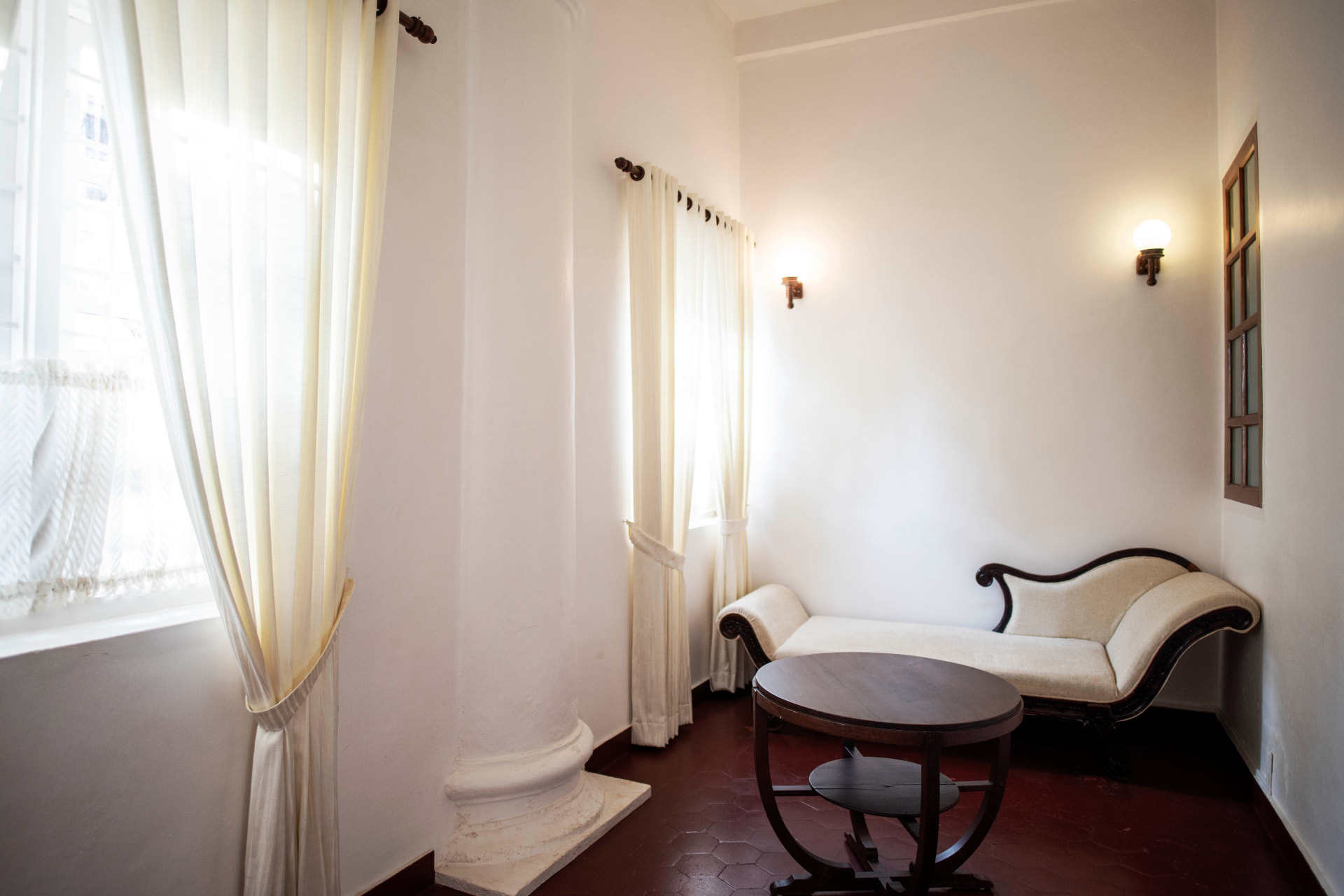 Sunlit alcove with chaise daybed and tall curtained windows
